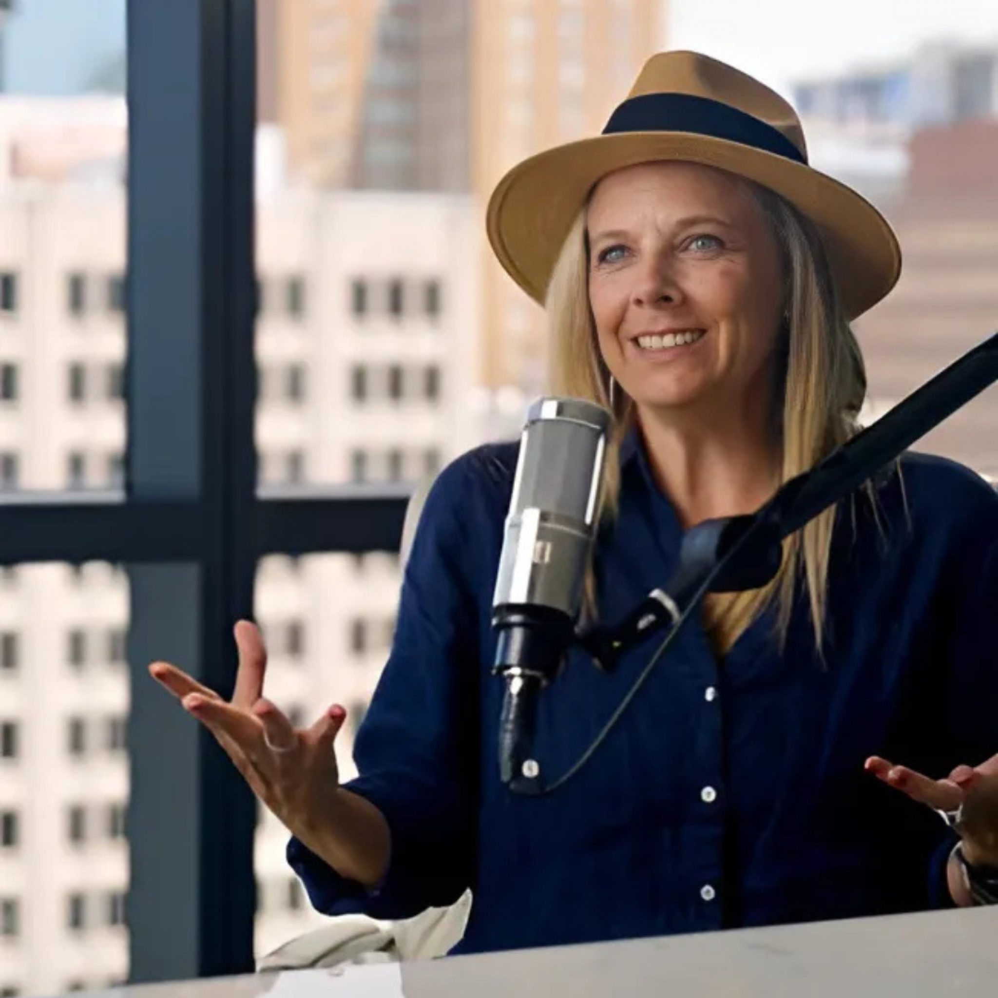 Woman speaking on stage wearing a hat during a presentation at the Home Design and Remodeling Show.