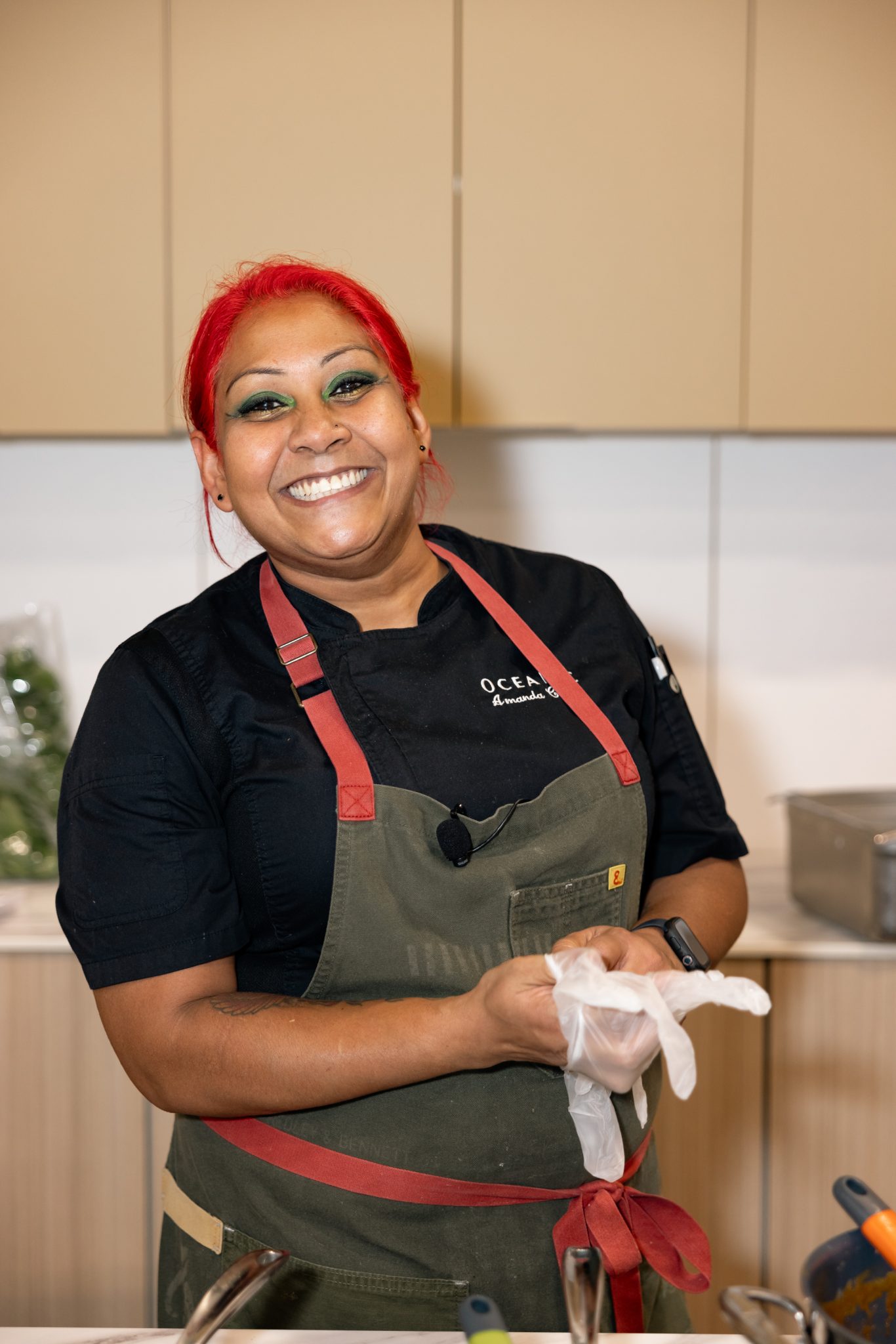 Chef smiling in black apron while preparing food during the Live Culinary Experience at the Home Design and Remodeling Show.