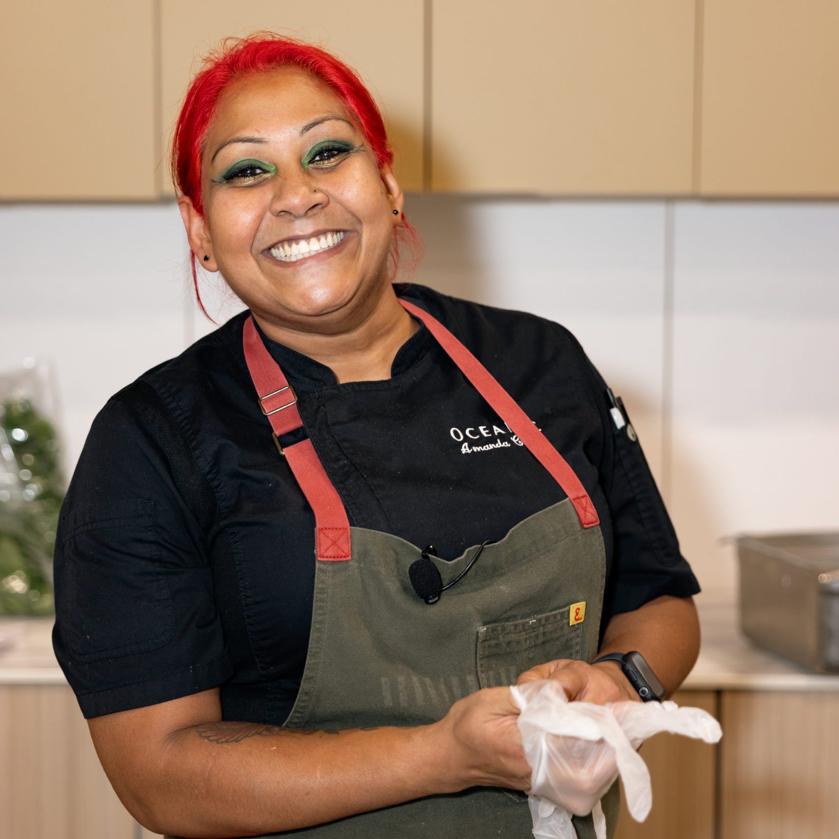 Chef smiling in black apron while preparing food during the Live Culinary Experience at the Home Design and Remodeling Show.