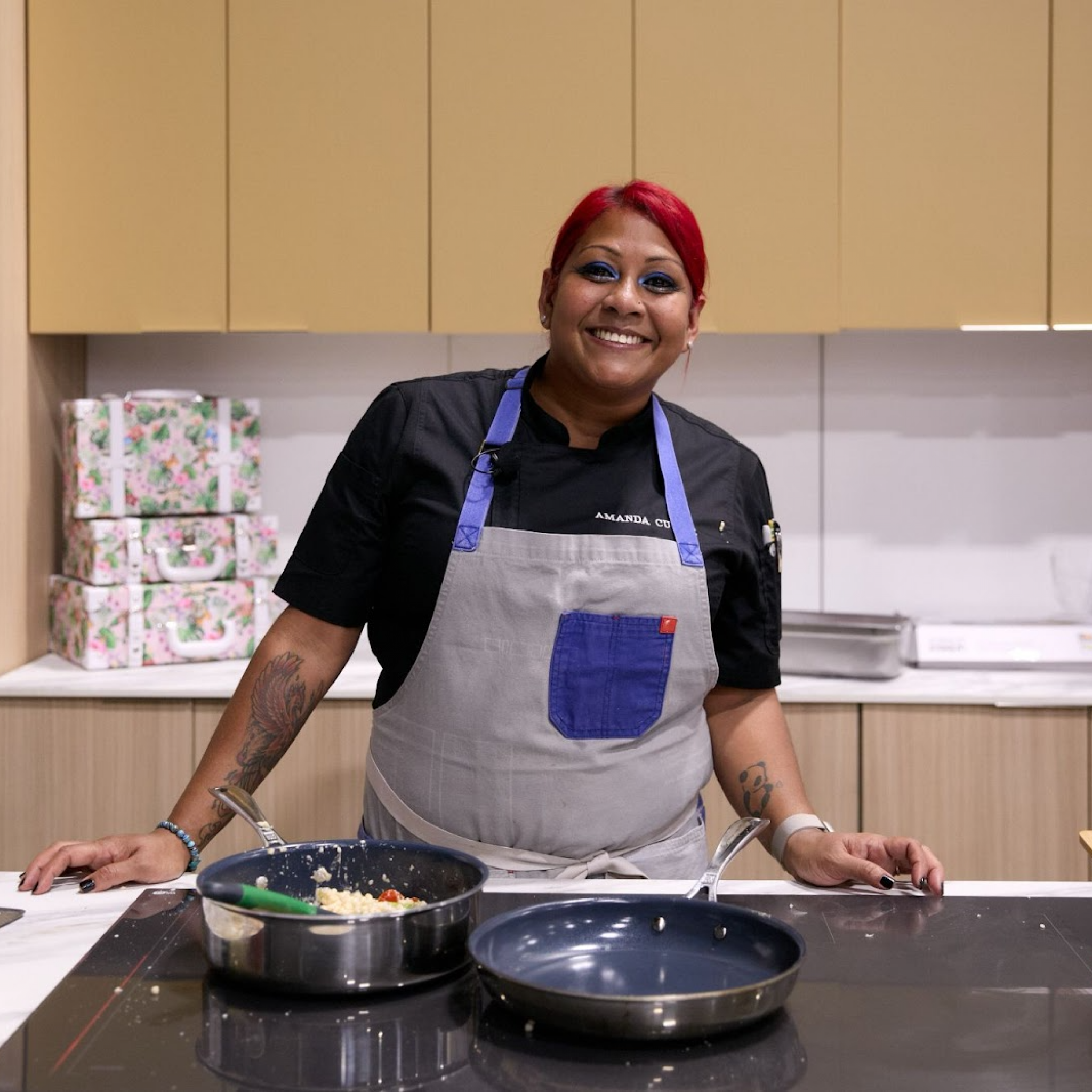 Chef smiling while preparing food on stage at the Home Design and Remodeling Show.