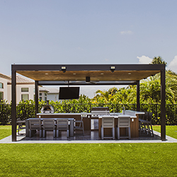Outdoor cooking and dining space with wooden pergola showcased at the Home Design and Remodeling Show.