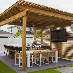 Pergola with bar seating and TV setup displayed in the outdoor living section of the Home Design and Remodeling Show.