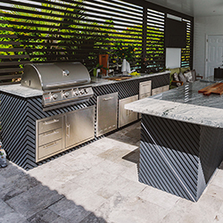 Modern outdoor kitchen setup with grill and seating area featured at the Home Design and Remodeling Show.