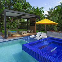 Backyard pool and shaded seating area featured in the Home Design and Remodeling Show outdoor living showcase.