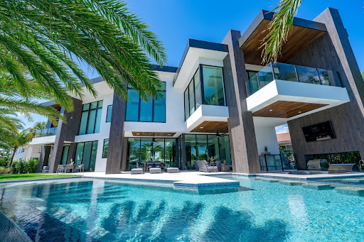 Modern luxury home exterior with pool and palm trees showcased at the Home Design and Remodeling Show.