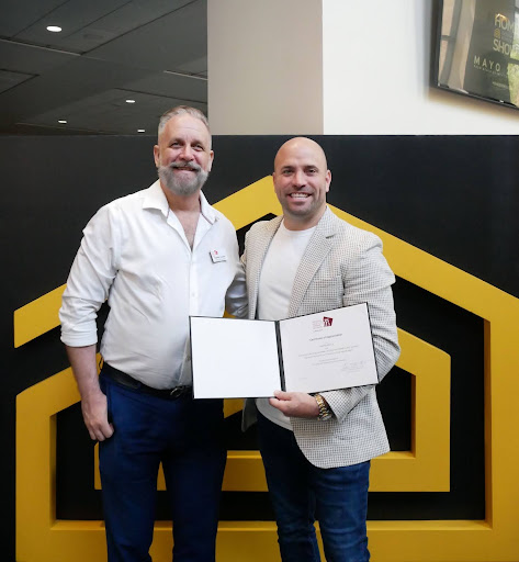 Two men holding certificates at the Home Design and Remodeling Show event.